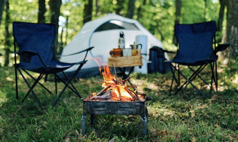 Photo of camp site with two folding chairs and fire