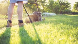 Photo of man mowing lawn. Keep Your Lawn Lush and Green in July.